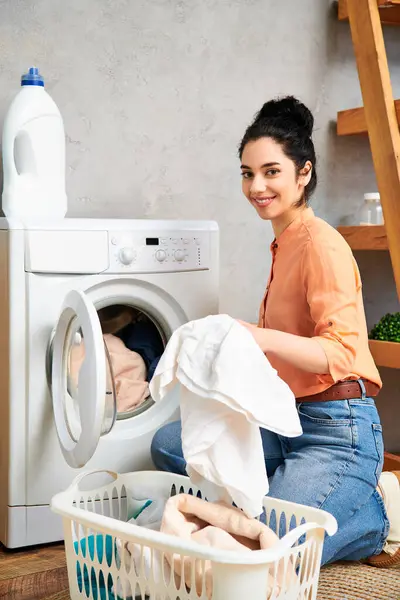 A stylish woman casually dressed, seated on the floor beside a washing machine. — Stock Photo
