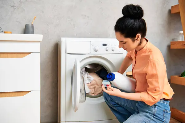 Une femme élégante verse de l'eau dans une machine à laver dans sa maison branchée pour nettoyer les vêtements. — Photo de stock