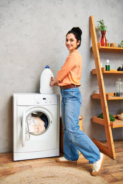 Una donna elegante in abbigliamento casual si erge con fiducia accanto a una lavatrice, pronta ad affrontare le faccende domestiche.. — Foto stock