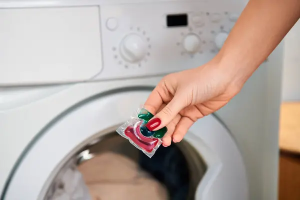 Une femme élégante tenant un sac de bonbons devant une machine à laver. — Photo de stock
