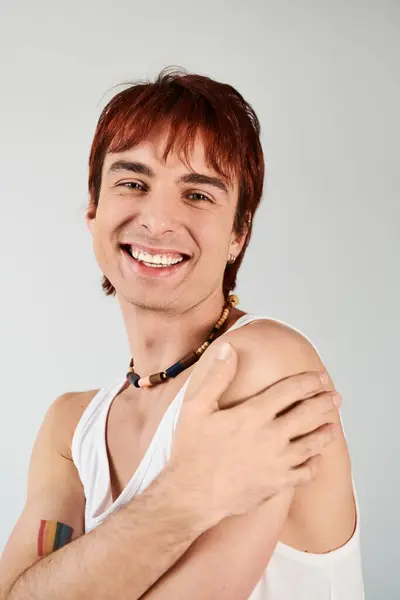 Stylish young man with red hair striking a pose in a white tank top against a grey studio background. — Stock Photo