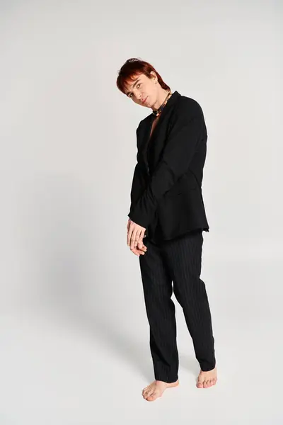 A stylish young man in a black suit striking a confident pose in front of a plain white background. — Stock Photo