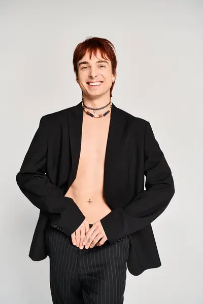 Un jeune homme élégant en costume pose avec confiance pour une photo sur fond de studio gris. — Photo de stock