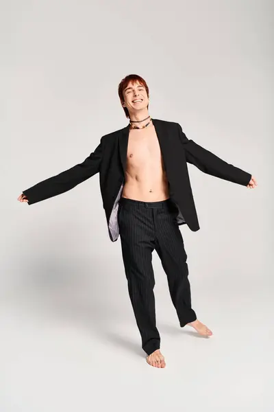 Um jovem elegante de terno faz uma pose confiante em um estúdio com um fundo cinza. — Fotografia de Stock