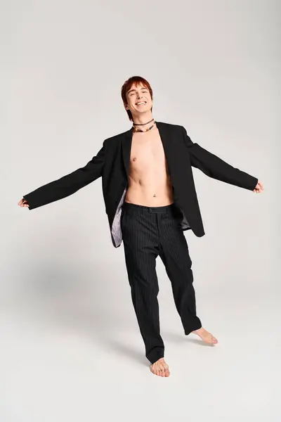 A stylish young man in a suit strikes a confident pose in a studio with a grey background. — Stock Photo