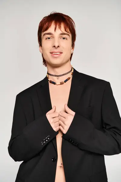 A stylish young man poses in a suit with his shirt open against a grey background, exuding confidence and sophistication. — Stock Photo