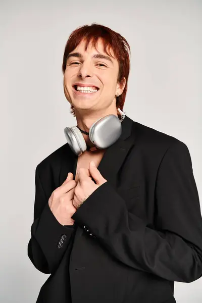 A stylish young man in a black suit posing with a pair of headphones. — Stock Photo