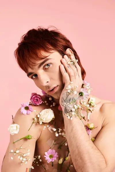 Joven con flores en el pecho, cogido de la mano, se levanta sobre el fondo del estudio en una pose de reflexión. - foto de stock