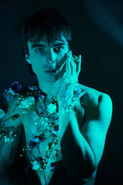 Un jeune homme avec des fleurs sur la poitrine tient ses mains sur son visage dans un geste contemplatif. — Photo de stock