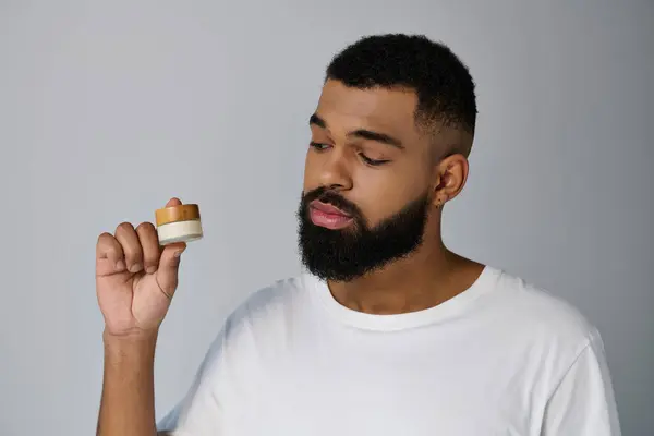 A man with a beard delicately holds cream. — Stock Photo