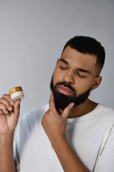 A bearded man holding cream. — Stock Photo