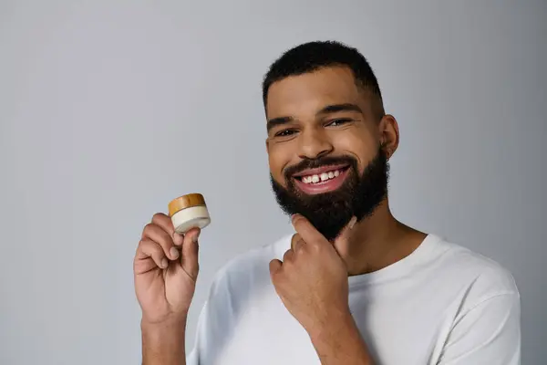 A bearded man holding a jar of cream. — Stock Photo