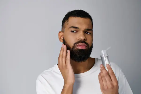 African american stylish man with a beard applying locion on his face. — Stock Photo