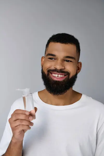 Handsome man with a beard holding a tube of locion. — Stock Photo