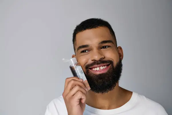 African american appealing man with a beard applying locion on his face. — Stock Photo
