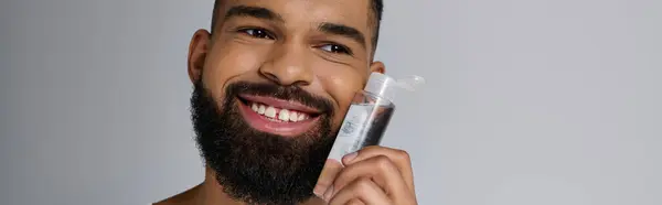 Afroamericano bello uomo con la barba applicazione locion sul suo viso. — Foto stock