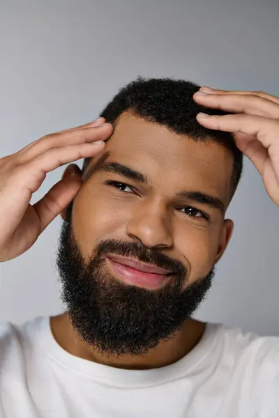 Joven afroamericano con barba cuidando su cabello. - foto de stock