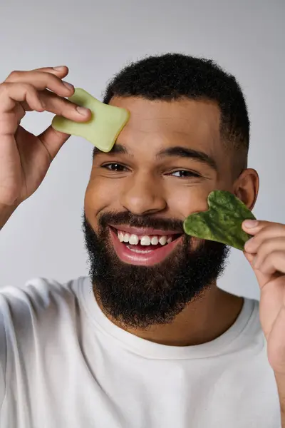 African american attractive man holds gua sha for skincare routine. — Stock Photo