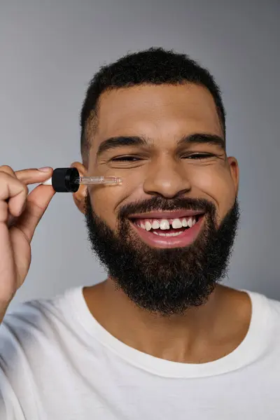 African american appealing young man with a beard holding a bottle of serum. — Stock Photo