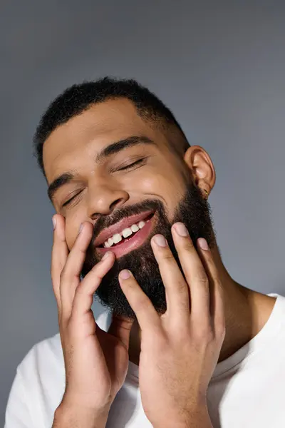 Uomo sorridente con la barba, mani sul viso. — Foto stock
