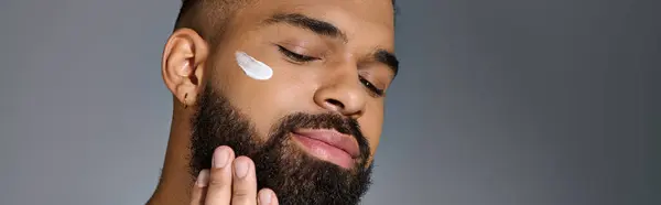 Um jovem bonito com barba e muito creme na cara. — Fotografia de Stock