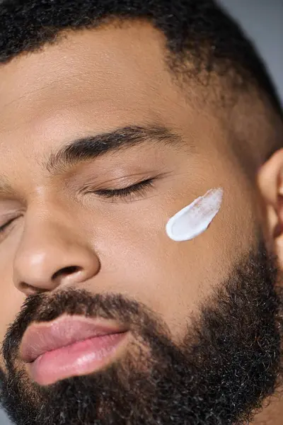 Close-up of a young man with a beard applying cream. — Stock Photo