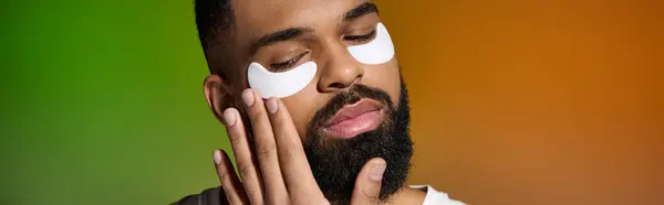 Un beau jeune homme avec des taches blanches sur le visage, se concentrant sur sa routine de soins de la peau. — Photo de stock