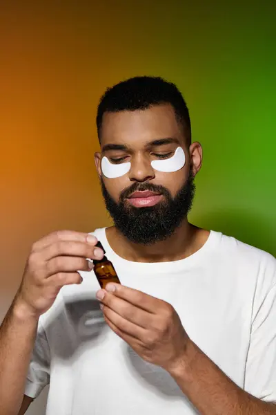 Hombre guapo afroamericano usando parches para los ojos y suero. - foto de stock
