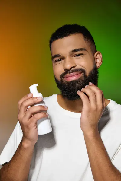 African american bearded man holds shaving cream. — Stock Photo