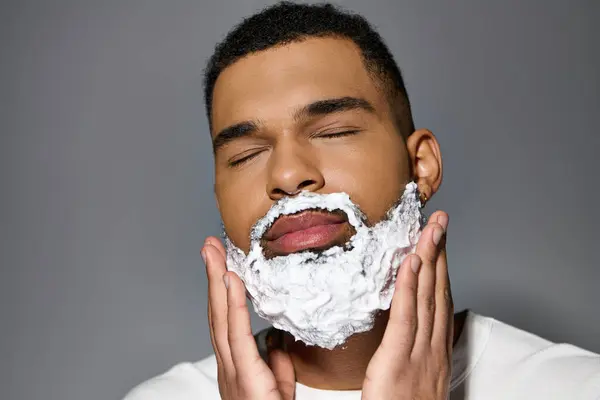 O homem barbudo afro-americano rapa de perto o rosto como parte de uma rotina de cuidados com a pele. — Fotografia de Stock