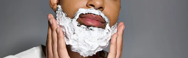 African american handsome man closely shaves his face as part of a skincare routine. — Stockfoto
