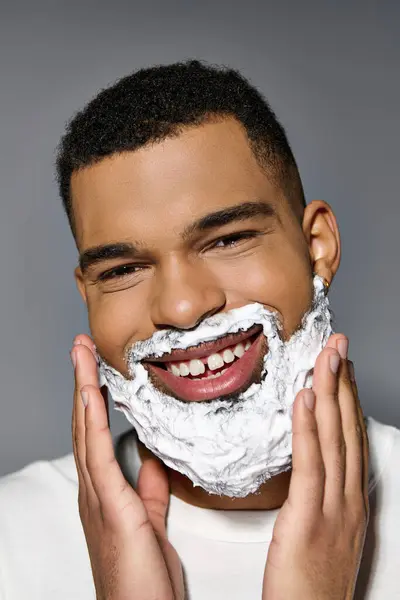 El hombre alegre afroamericano se afeita de cerca la cara como parte de una rutina de cuidado de la piel. - foto de stock