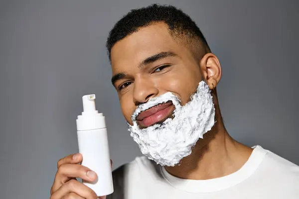 Handsome man with beard holds shaving bottle. — Stock Photo
