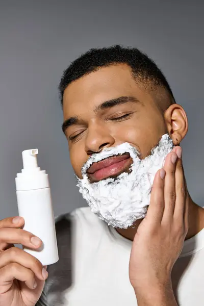 Joven guapo afroamericano cuidadosamente se afeita la cara. - foto de stock