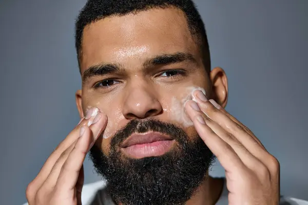 A bearded man gently shaves his face in his skin care routine. — Stock Photo
