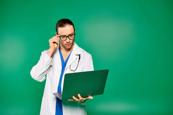 Bello medico in camice bianco tiene computer portatile. — Foto stock