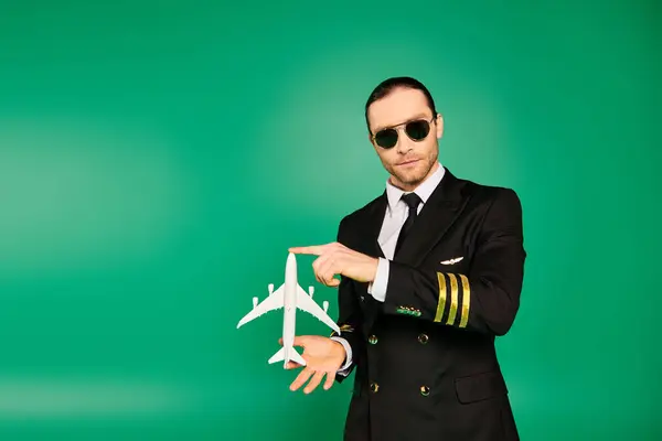 Uomo elegante in tuta nera e occhiali da sole con in mano un modello di aeroplano. — Foto stock