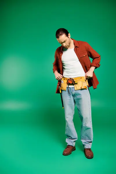 Un hombre de uniforme sostiene con confianza las herramientas contra un exuberante telón de fondo verde. - foto de stock
