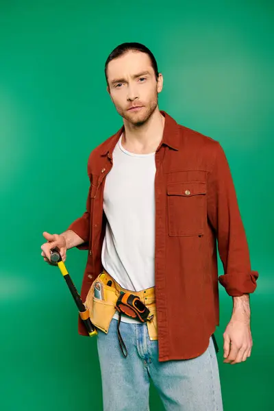 Un beau travailleur masculin en uniforme avec une ceinture à outils sur fond vert. — Photo de stock