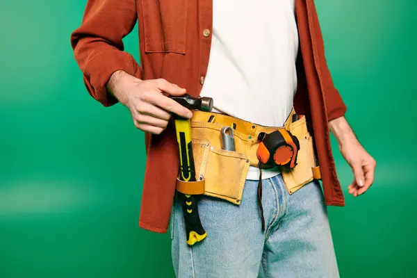 Beau travailleur en uniforme tenue ceinture d'outils sur fond vert. — Photo de stock