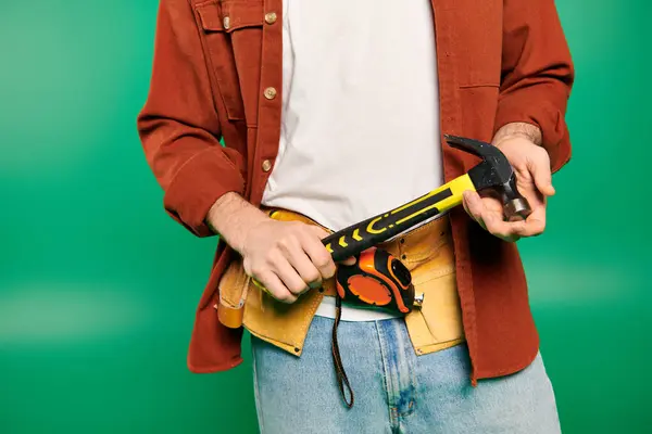 Hombre guapo trabajador en uniforme posando con martillo sobre fondo verde. - foto de stock
