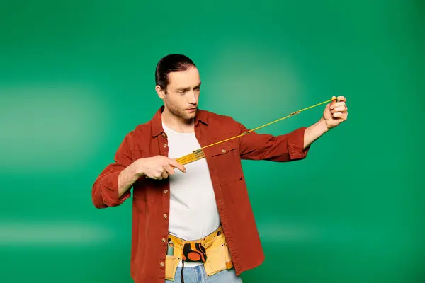 Un homme en chemise rouge tient avec confiance un ruban à mesurer. — Photo de stock