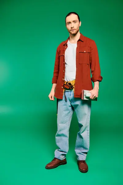Un trabajador masculino guapo en uniforme con herramientas posando sobre un fondo verde. - foto de stock