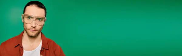 A man wearing glasses poses against a vivid green background. — Stock Photo