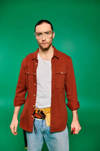 Schöner Arbeiter in Uniform mit Brille vor grünem Hintergrund. — Stockfoto