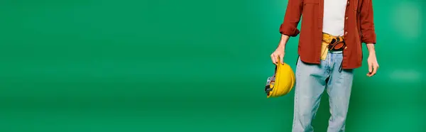 A worker in uniform holds a helmet in front of a green screen backdrop. — Stock Photo