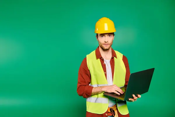 Ein Mann in gelber Warnweste hält einen Laptop in der Hand. — Stockfoto