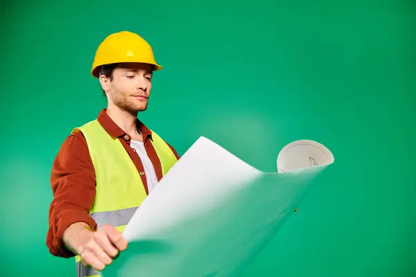 Un hombre guapo con un sombrero duro sostiene un plano con confianza. - foto de stock