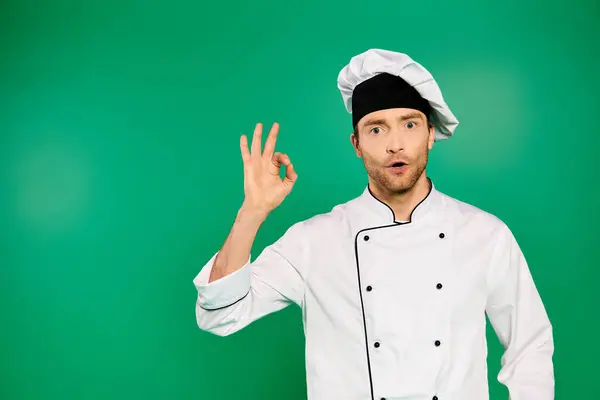 Bello chef maschio in uniforme bianca che fa segno OK su sfondo verde. — Foto stock