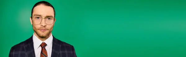 Handsome businessman in chic suit and tie, wearing glasses, striking a pose on a green backdrop. — Stock Photo
